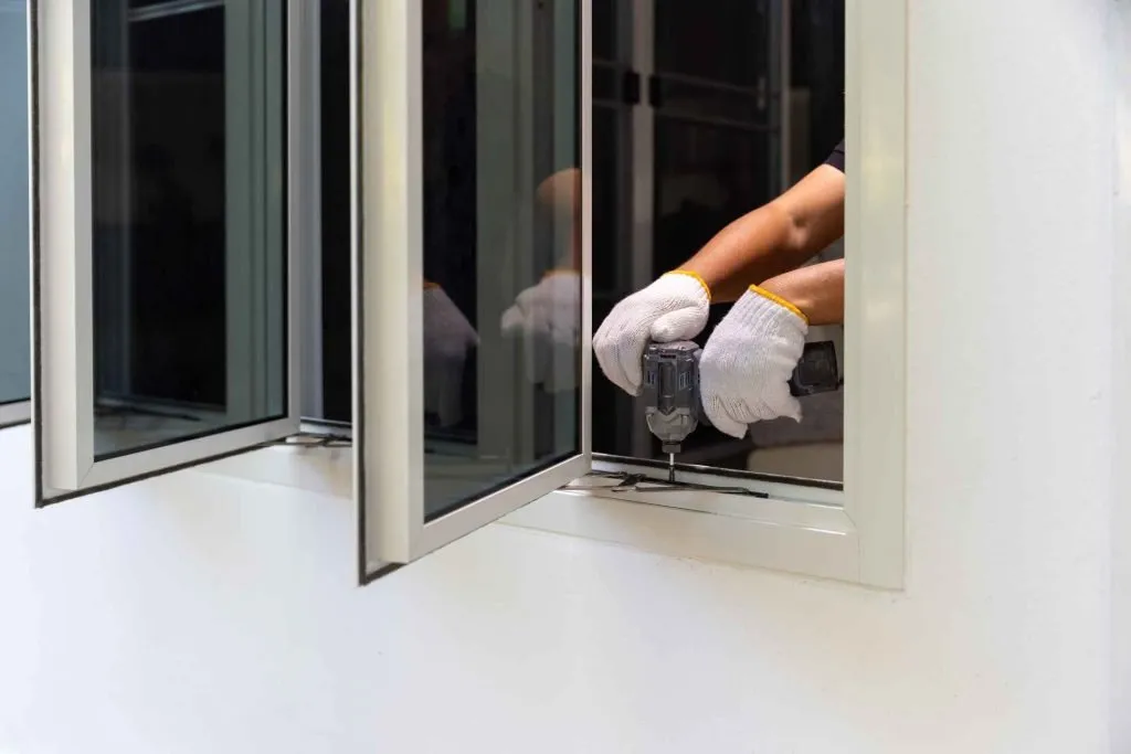 A person is using a cordless drill to install a window.